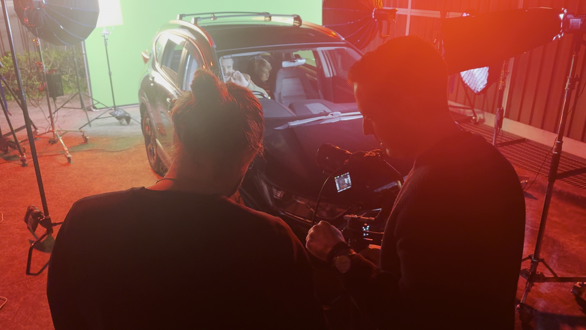 Two crew members behind camera watching actor perform